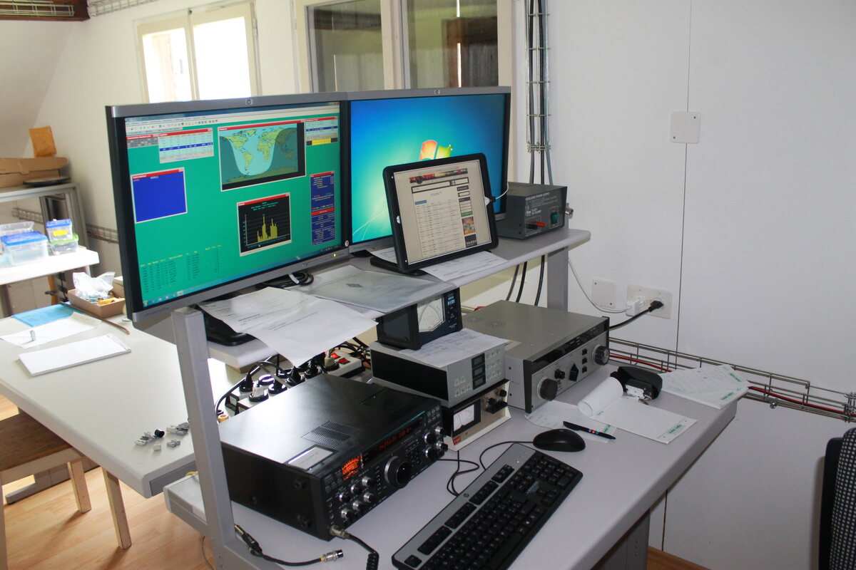 Kurzwellenstation mit Transceiver, Tastatur und zwei Monitoren, auf denen Funksoftware läuft